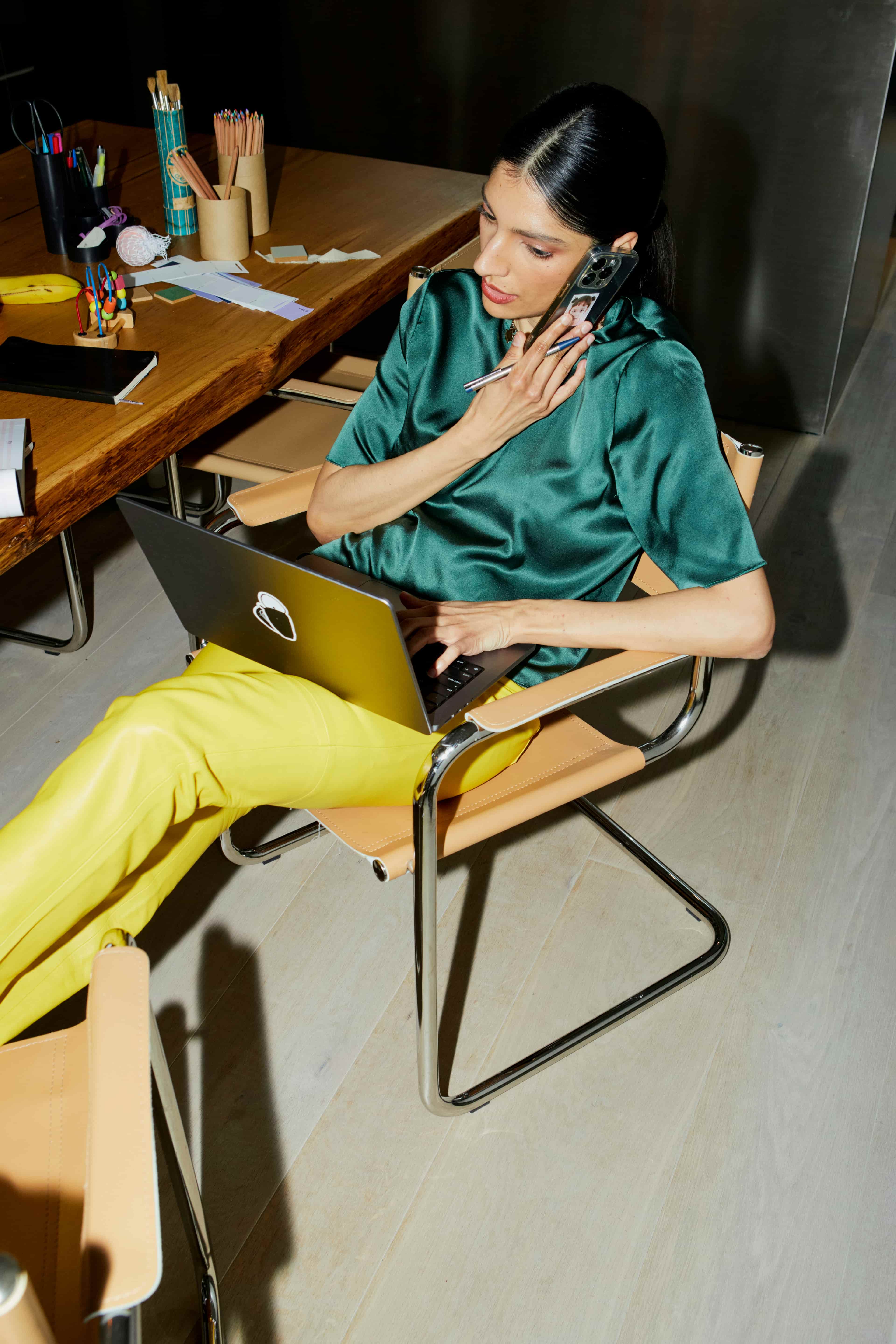 Een vrouw met een telefoon in de hand en een laptop op schoot